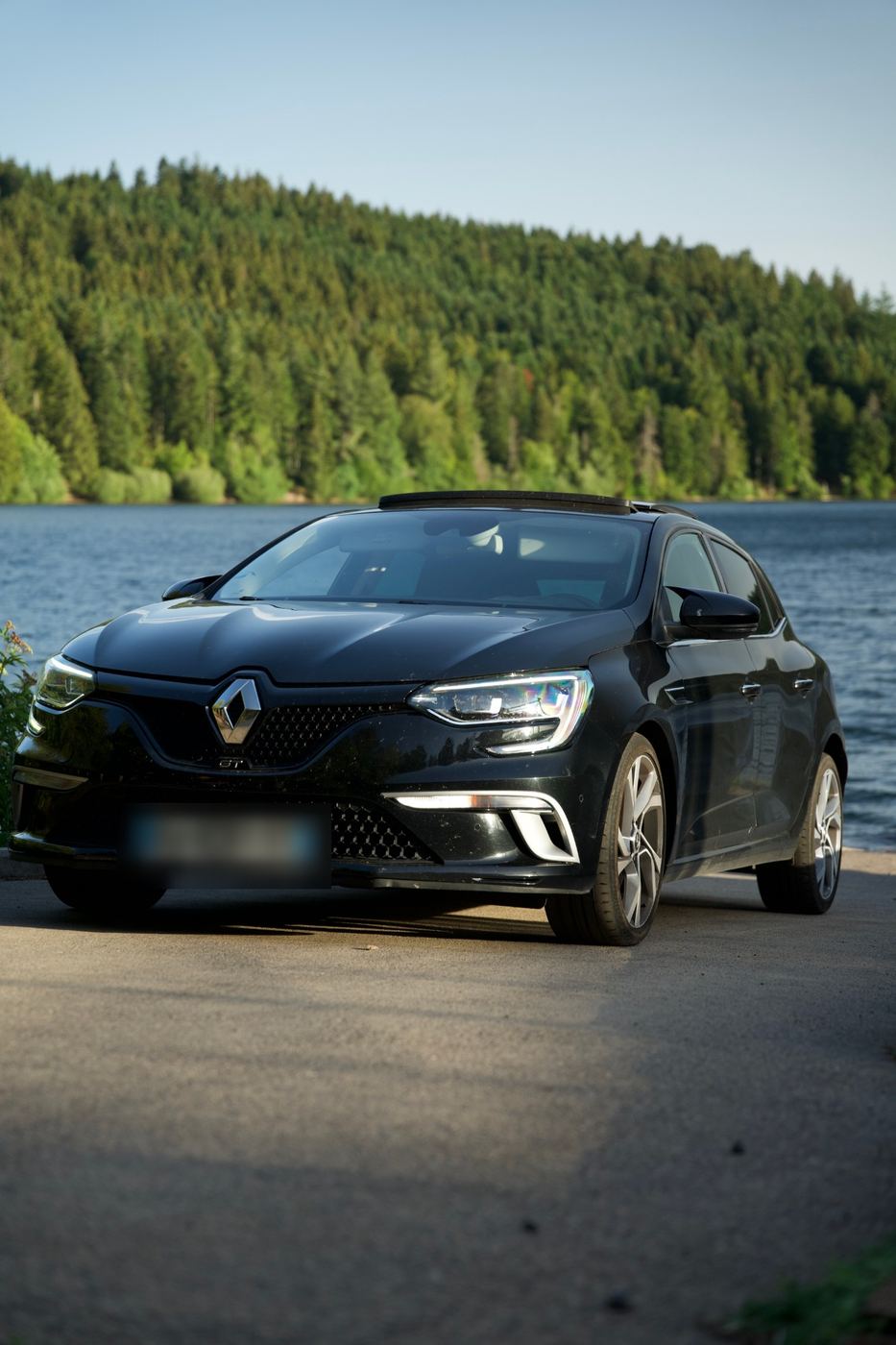 Renault Mégane 4 GT noire photographiée de trois quarts au bord du lac